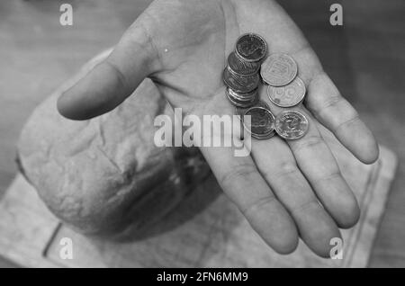 Ultimo denaro per acquistare il pane. Un pane e la mano di un vecchio. Ci sono alcune monete nella palma. Foto Stock