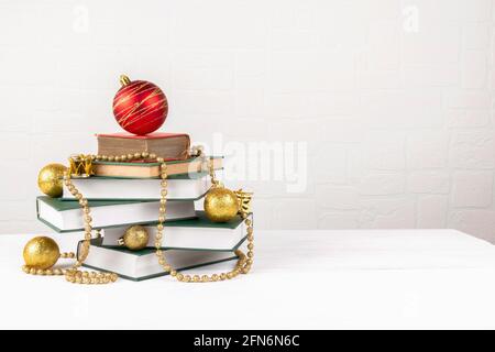 Albero di Natale fatto di libri su tavola su sfondo muro di mattoni Foto Stock