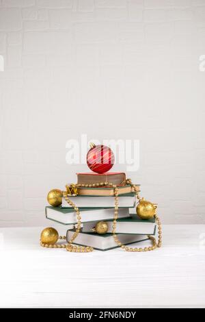 Albero di Natale fatto di libri su tavola su sfondo muro di mattoni Foto Stock