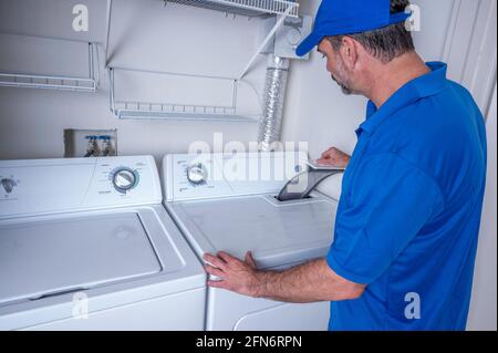 Tecnico professionale di apparecchi che controlla un sifone in un ambiente residenziale essiccatore Foto Stock
