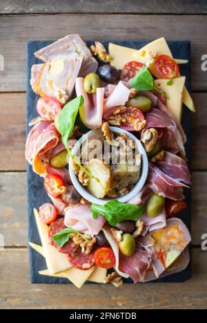 tabella piena di prodotti mediterranei quali frutta a guscio, prosciutto, formaggio, olive, pomodoro, melanzane, olive, pomodoro, melanzane. Foto Stock