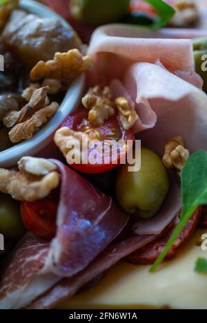 tabella piena di prodotti mediterranei quali frutta a guscio, prosciutto, chee, olive, pomodoro, melanzane. Foto Stock