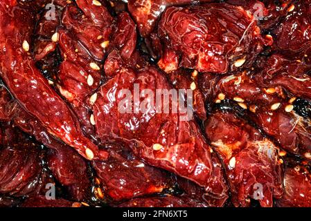 Fette di manzo marinate, luminose e succose, con spezie, olio e semi di sesamo Foto Stock