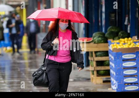 Londra, Regno Unito. 13 maggio 2021. Una donna si rifuga dalla pioggia sotto un ombrello a Londra. Credit: SOPA Images Limited/Alamy Live News Foto Stock