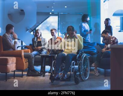 Ritratto di una donna d'affari disabile su una sedia a rotelle di fronte il suo team aziendale in ufficio Foto Stock