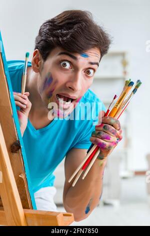 Il giovane artista divertente lavorare sulla nuova pittura nel suo studio Foto Stock