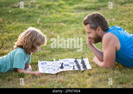 Padre e figlio giocano a scacchi trascorrendo il tempo insieme all'aperto. Foto Stock