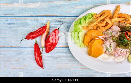 Cibo peruviano: Ceviche di pesce e chicharron de pescado con manioca fritta, mais dolce e patate dolci, servito su un piatto bianco, tradizionale peruviana c Foto Stock