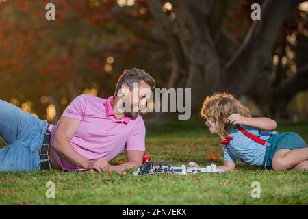 Padre e figlio giocano a scacchi trascorrendo il tempo insieme all'aperto. Bambino intelligente, bambini intelligenti. Foto Stock