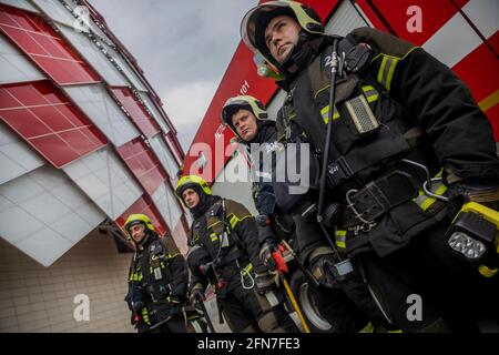 Mosca, Russia. 14 maggio 2021. Di fronte a un camion dei vigili del fuoco e all'edificio dello stadio di calcio Otkritie Arena a Mosca, in Russia, si trova un vigile del fuoco. Lo stadio di calcio Otkritie Arena è sede della squadra di calcio Spartak Foto Stock