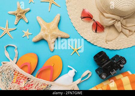 Composizione piatta con diversi accessori per una vacanza al mare su sfondo blu, sfondo estivo. Foto Stock