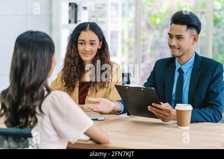 Senior Asian Manager che spiega o risponde sulla descrizione del lavoro e. Benefici per giovane donna asiatica laureata con movimento positivo dentro Sala meeting, autobus Foto Stock