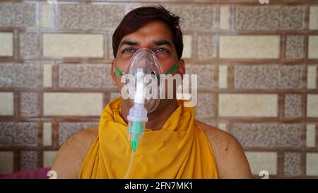 L'uomo indiano infettato con la malattia di Covid 19. Maschera per l'inalazione di ossigeno con flusso di ossigeno liquido. Foto Stock