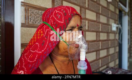 03 maggio 2021 - Reengus, Sikar, India. Vecchia donna indiana infettata con la malattia di Covid 19. Maschera per l'inalazione di ossigeno con flusso di ossigeno liquido. Foto Stock