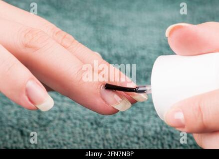 Donna che utilizza nailpolish trasparente durante la realizzazione stessa manicure Foto Stock