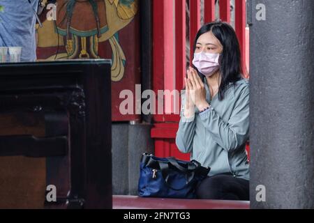 Taipei, Taiwan. 13 maggio 2021. Una donna che indossa una maschera facciale prega all'interno del tempio Longshan a Taipei in mezzo a un'impennata di casi Covid19. Il Centro centrale di comando per le epidemie (CECC) di Taiwan ha riportato un totale di 180 nuovi casi COVID-19 e ha portato il livello di allarme al livello 3 a Taipei. Credit: SOPA Images Limited/Alamy Live News Foto Stock