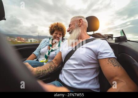 Felice coppia senior che si diverte a guidare su una nuova auto convertibile - persone mature che si divertono insieme durante la vacanza di viaggio su strada Foto Stock