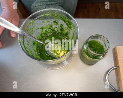 Pesto Ramson e ingredienti per cucinarlo su un tavolo da cucina. Riempimento del vetro Foto Stock