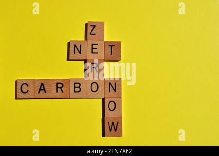 NET, Zero, Carbon, Now, parole in lettere alfabetiche in legno in forma di crossword isolate su sfondo giallo con spazio di copia Foto Stock