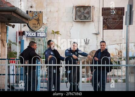 Gerusalemme, Israele. Quattro agenti di polizia hanno pausa caffè presso la corte della stazione di polizia. In caso di emergenza, la polizia può essere raggiunta chiamando il numero 100. Foto Stock