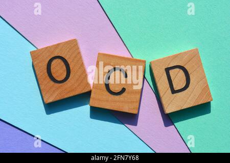 OCD acronimo di disturbo compulsivo ossessivo in lettere alfabetiche in legno su sfondo colorato Foto Stock