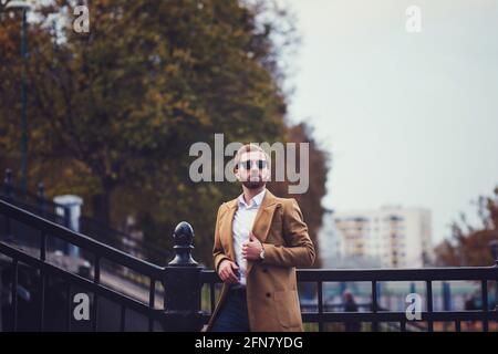 bell'uomo con setole in un cappotto autunnale si alza il ponte Foto Stock