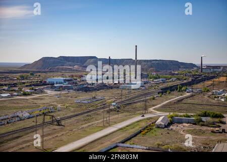 Vista aerea su stazione ferroviaria, strada, pile di fumo di lavorazione e impianto termoelettrico, e discariche minerarie all'orizzonte. Cielo blu. Foto Stock