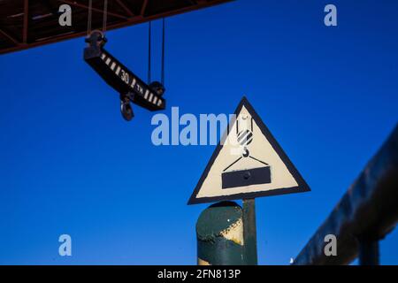 Segnale auto-fatto vintage 'Crane Working' contro il cielo blu profondo. Carroponte sullo sfondo, sfocato. Foto Stock