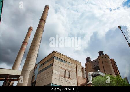Temirtau, Kazakhstan: Vecchio impianto sovietico di cemento vecchio fumo stack e edificio industriale. Vista panoramica in prospettiva. Foto Stock