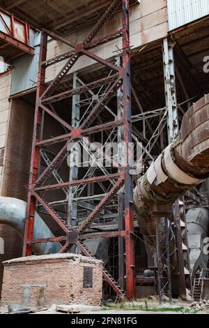 Temirtau, Kazakhstan - 09 giugno 2012: Supporto di apertura in metallo del trasportatore. Elementi in metallo verniciato rosso arrugginito. Su pianta di cemento sovietica obsoleta. Foto Stock