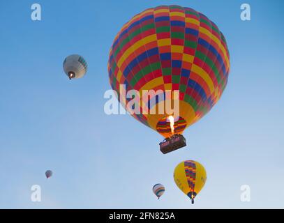 Tiro ad angolo basso di un grande pallone ad aria calda sul fuoco e altri palloncini più piccoli. Foto Stock