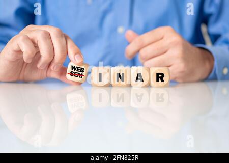 Primo piano delle mani di un uomo che fanno la parola "webinar" con cubetti di legno Foto Stock