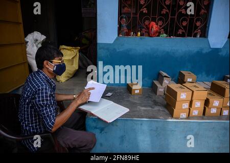 Tehatta, Bengala Occidentale, India. 15 maggio 2021. Il coronavirus è entrato nelle zone rurali dell’India. Essendo un centro di quarantena in una scuola primaria di villaggio, gli studenti stanno avendo scarpe in distribuzione annuale da parte del governo del Bengala Occidentale in una casa vicina dalla scuola al villaggio di Nabin Nagar. Le scarpe degli studenti sono state date ai loro genitori a causa della minaccia del coronavirus. La maggior parte di loro sono guardiani che non sono così ben istruiti. Il programma è fatto con precauzione e sicurezza, con distanza sociale e l'uso di igienizzatore per le mani. Foto Stock