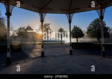 Il sole sorge dietro il padiglione nel Parco di Mesnes a Wigan, Greater Manchester Foto Stock