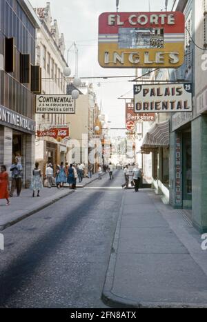 Una strada secondaria, Heerenstraat, a Willemstad, Curao alla fine degli anni '50. Willemstad è la capitale di Curao, un'isola del sud dei Caraibi che è un territorio olandese. Il centro della città, con la sua architettura unica, è un sito patrimonio dell'umanità dell'UNESCO. La lingua parlata è Papiamento, una lingua portoghese, anche se le insegne per la strada sono un mix di principalmente spagnolo e inglese. Oggi la strada è pedonale e gli edifici dipinti in colori luminosi 'patrimonio'. Questa immagine proviene da una vecchia trasparenza amatoriale del colore – una fotografia d'epoca degli anni '50. Foto Stock