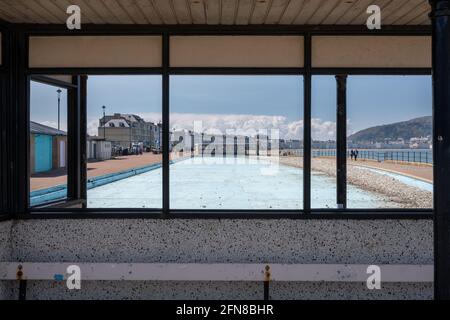 La piscina pubblica per bambini a Llandudno, vista da una gallerie si trova svuotata e si trova abbandonata piena di ciottoli dalla spiaggia. Foto Stock