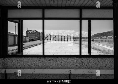 Una fotografia in bianco e nero che mostra la piscina pubblica per bambini A Llandudno visto da una gallerie di osservazione si trova svuotato e. menzogne abbandonate piene di pedone Foto Stock