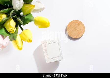 Candele di soia in bottiglie di vetro bianco con coperchio e fiori di tulipani, su sfondo bianco. Foto Stock