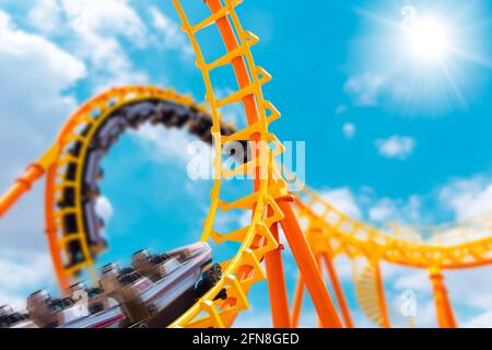 le montagne russe più eccitanti si guidano in alto al cielo estivo al parco a tema, la gente eccita divertimento e macchina gioiosa da gioco in vacanza. Foto Stock