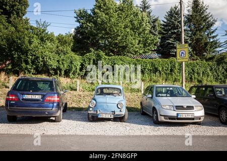 Immagine di un'auto blu vintage Zastava 750 parcheggiata vicino a auto più moderne in un parcheggio di Belgrado, Serbia. Il Zastava 750 era un supermini prodotto da t Foto Stock