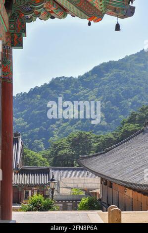 Tempio buddista coreano dall'epoca della dinastia Silla. Vista della catena montuosa boschiva con Daeungjeon Hallto sulla sinistra. Tempio Haeinsa, Monte Gaya, Gayasan Na Foto Stock