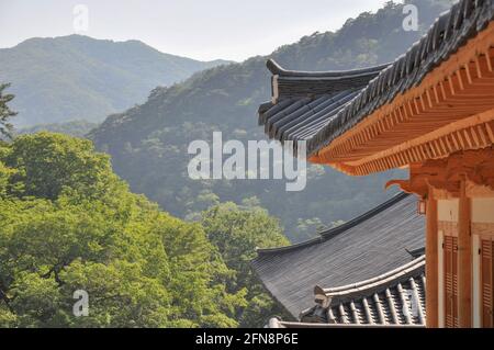 Tempio buddista coreano dall'epoca della dinastia Silla. Si presenta con un particolare di un tradizionale tempio con una catena montuosa boschiva sullo sfondo. Tempio Haeinsa, Foto Stock