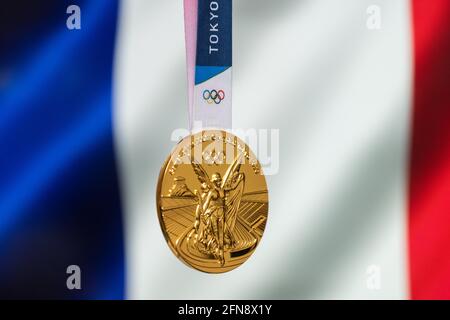 25 aprile 2021 Tokyo, Giappone. Medaglia d'oro dei XXXII Giochi Olimpici estivi 2020 a Tokyo sullo sfondo della bandiera della Francia. Foto Stock