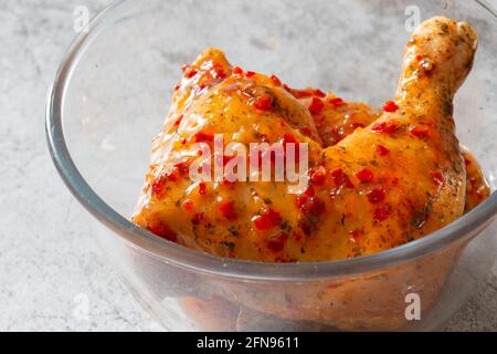 Pollo con salsa piri o peri marinata in un recipiente di vetro. Su sfondo concreto Foto Stock