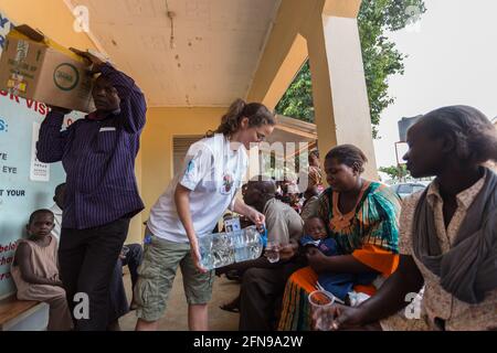 Un medico straniero sta dando acqua potabile ai pazienti in attesa in una clinica medica a Mbale, nella rurale Uganda orientale Foto Stock