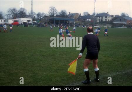 Un uomo di linea con una bandiera gialla sta guardando la partita in un campo di calcio non campionato Foto Stock