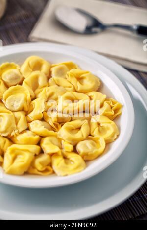 Tortellini italiani in brodo su un piatto. Foto Stock