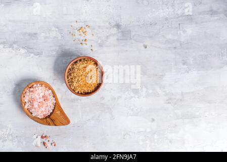 Sale e zucchero nella vista dall'alto della ciotola di legno. Sale di roccia rosa dell'Himalaya e zucchero di canna grezzo. Foto Stock