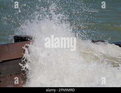 Onde che stanno schiantando contro la difesa del mare di legno. Foto Stock