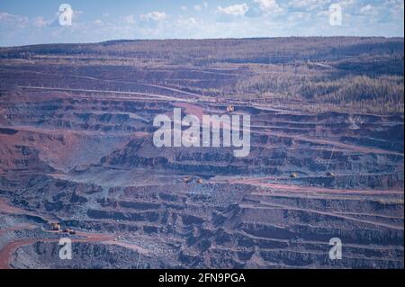 Vista di una parte di una cava di minerale di ferro con varie sfumature di quarzite rosa e blu e terrazze per la rimozione di minerale. Sfondo. Copiare lo spazio. Foto Stock